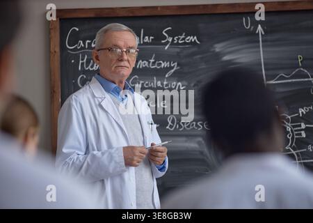 Portrait of Senior Male Professor Teaching Cardiology to Students Stock Photo