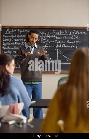 Vertical of Black Male Teacher Explaining Economics Lesson in Classroom Stock Photo