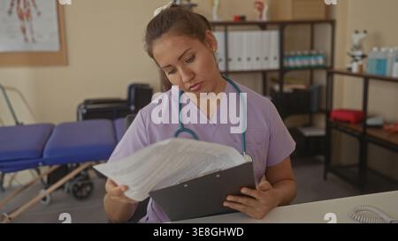 Young woman doctor holding clipboard and reading patient forms in a clinic building; compassion fatigue. Stock Photo