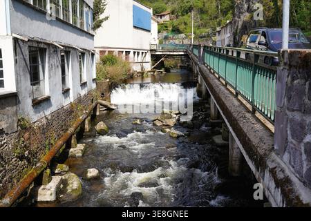 THIERS, FRANCE - MARCH 28, 2026: Small waterfall on urban river with old industrial buildings Stock Photo