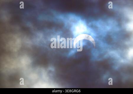 Partial solar eclipse viewed through dramatic clouds in Boise, Idaho on October 14, 2023. Stock Photo