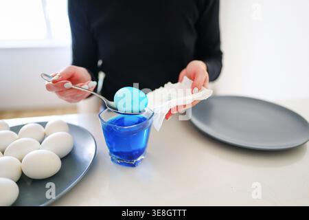 Hands mixing blue dye for eggs, DIY Easter decoration and seasonal tradition. Stock Photo