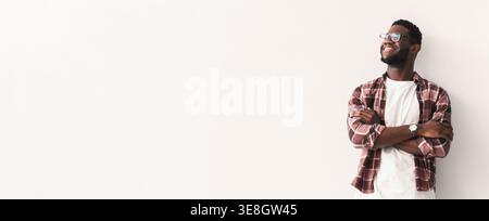 Man Stands and Smiles While Leaning Against a Wall With Arms Crossed in a Bright Space Stock Photo