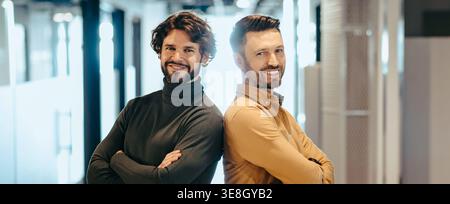 Two Men Stand Back to Back in a Modern Office Setting During Daytime Stock Photo
