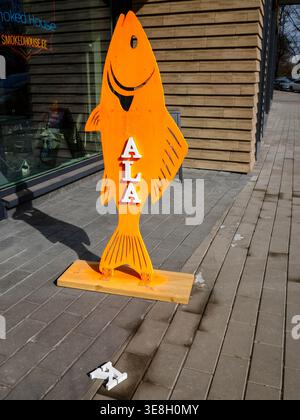 Orange wooden fish sign reading KALA outside Smoked House restaurant on sidewalk in Kalamaja, Tallinn, Estonia, spring Stock Photo