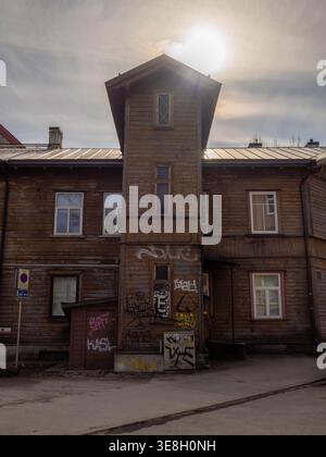 Graffiti-covered wooden house with stairwell tower backlit by hazy sun in Kalamaja district, Tallinn, Estonia Stock Photo