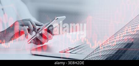 User Interacts With Mobile Device While Analyzing Market Data in a Busy Office Setting Stock Photo