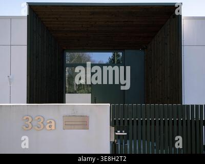 Modern residential entrance with dark wood cladding and green metal fence in Kristiine, Tallinn, Estonia, spring Stock Photo