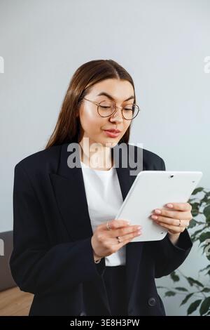 Woman using tablet and reading information. Beautiful businesswoman analyzing data. Female professional working in modern corporate office environment Stock Photo