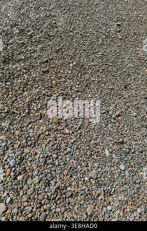 Vertical overhead shot of natural beach pebbles and stones on a mediterranean shore with copy space. High resolution organic texture for travel market Stock Photo