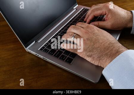 Close-up of hands typing on laptop keyboard, representing concentration, productivity and digital workflow. Stock Photo