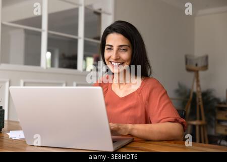 Smiling woman working on laptop at home Stock Photo