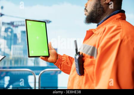 Chroma key tablet used by offshore platform worker configuring boat management systems for more efficient oil extraction. Man working on drilling rig doing seabed analysis using isolated screen device Stock Photo