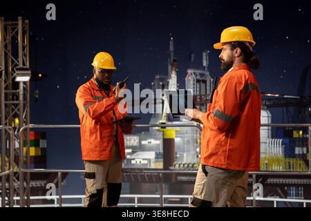 Offshore sea platform technicians using deep learning artificial intelligence to optimize drilling precision. Drilling rig crew monitors equipment performance using AI neural networks tracking system Stock Photo