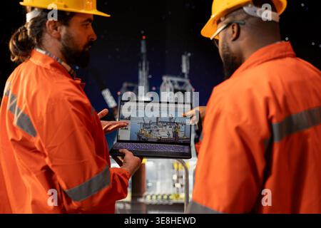 Offshore platform crew staff members checking equipment status indicators on laptop system dashboard. Coworkers doing brainstorming, using notebook digital monitoring panel Stock Photo