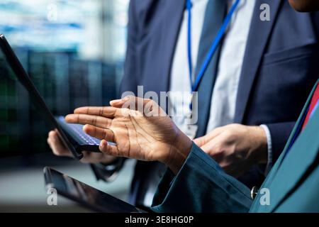 Data center coworkers cooperating, using devices to upgrade cloud storage hardware. Engineering team brainstorming, talking in server hub, updating electronics systems using applications Stock Photo