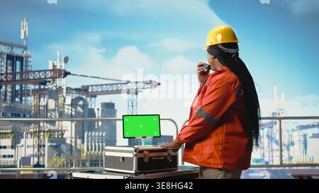 Isolated screen tablet used by drilling rig expert to monitor systems, talking in handheld radio. Offshore platform technician using walkie talkie, calibrating gear with chroma key device, Stock Photo