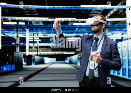 Using VR headset gear, technology and programmer in data center managing enterprise technology solutions. Supervising IT operations, virtual reality simulation and employee in futuristic server room Stock Photo
