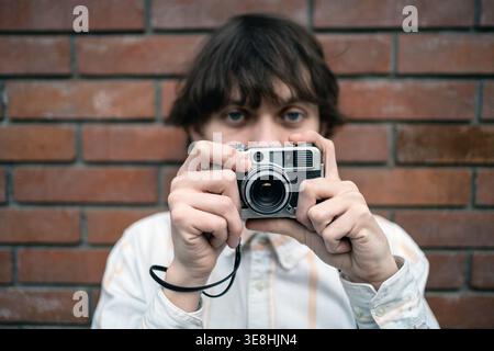 Analog photography young man holding vintage camera, retro lifestyle, nostalgia concept, youth creativity. Stock Photo