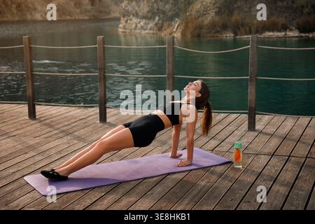 Outdoor fitness. Beautiful woman performing reverse plank pose. Female improving body control and strength. Wellness lifestyle. Stock Photo