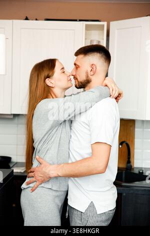 Close-up of a young couple hugging in a cozy kitchen. Concept of intimacy, love, and emotional connection. Stock Photo