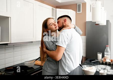 Young couple hugging during cooking at home. Concept of love and intimacy. Stock Photo