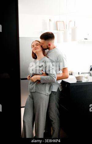 Young couple embracing in kitchen during cooking. Concept of love, lifestyle and relationships. Stock Photo