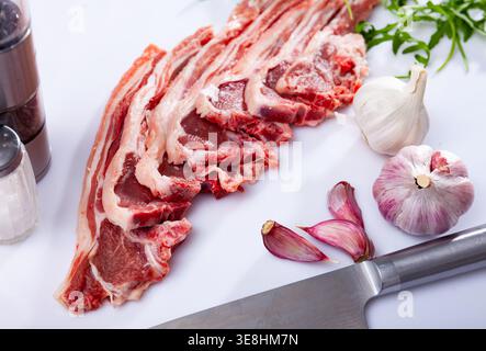 Raw lamb chops on kitchen table with garlic, arugula, spices Stock Photo