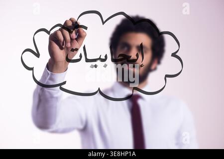 Businessman writing the Arabic word for positivity on glass conveying optimism and creative thinking Stock Photo