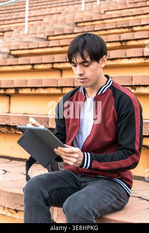 Young man studying drawing on tablet outdoors Stock Photo