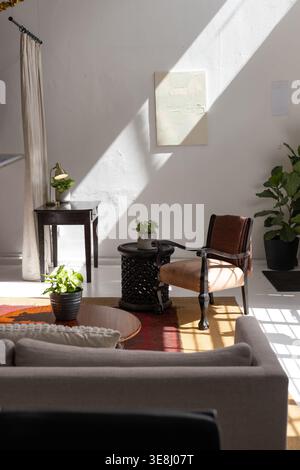 Sunlight casting through window bathing rust armchair, highlighting carved side table, copy space Stock Photo