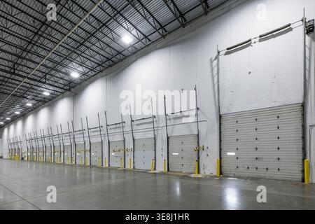 Interior row of loading dock doors with yellow bollards in an empty warehouse, Clifton, NJ Stock Photo