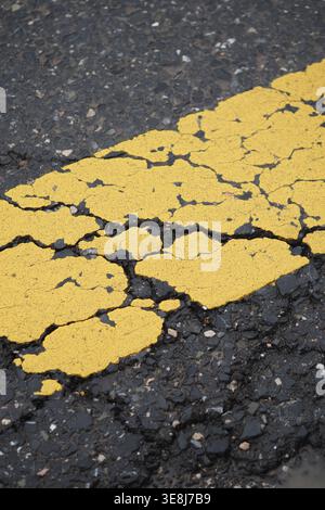Cracked yellow lines on asphalt road surface Stock Photo