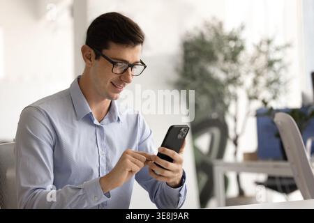 Smiling businessman using smartphone at workplace desk Stock Photo