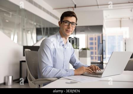 Male employee in casual shirt working online using modern laptop Stock Photo