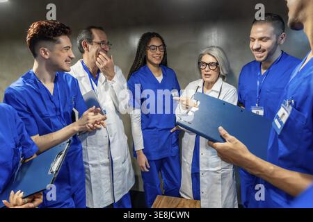 Diverse medical team collaborating and discussing patient records, sharing knowledge and expertise in a hospital setting, illustrating teamwork and he Stock Photo