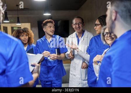 Healthcare team of doctors and nurses collaborating, smiling, and discussing patient care in a modern hospital setting, fostering teamwork and profess Stock Photo