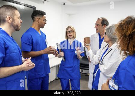 Diverse medical team members, including doctors and nurses, collaborating and sharing ideas during a break or informal meeting in a modern clinic or h Stock Photo