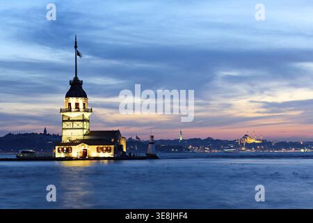 Sunset lights up Maiden's Tower on the Bosphorus in Istanbul. The sky shows warm colors and the tower stands tall against the water Stock Photo