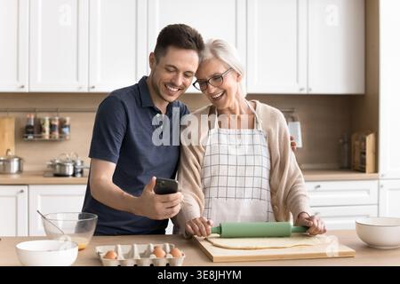 Multigenerational family using smartphone while cooking in kitchen Stock Photo