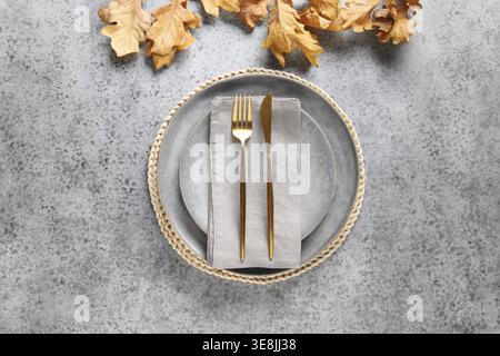 Autumn table setting decorated dry oak leaf and golden cutlery on gray table for Thanksgiving day. View from above Stock Photo