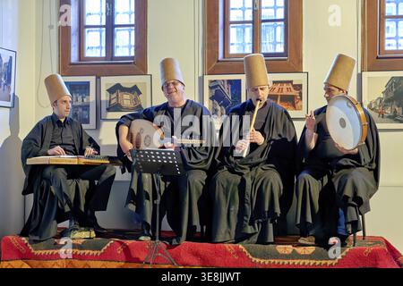 Four musicians play traditional instruments in Istanbul Turkey while whirling dervishes perform during a sufi event. The atmosphere is lively Stock Photo