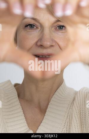 Portrait of happy woman. Female hands making sign Heart by fingers. Looking at camera. Stock Photo