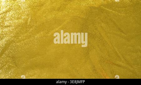 Slightly crumpled gold foil texture with reflective surface and organic metallic creases Stock Photo