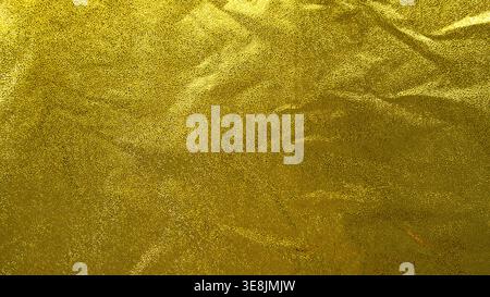 Slightly crumpled gold foil texture with reflective surface and organic metallic creases Stock Photo