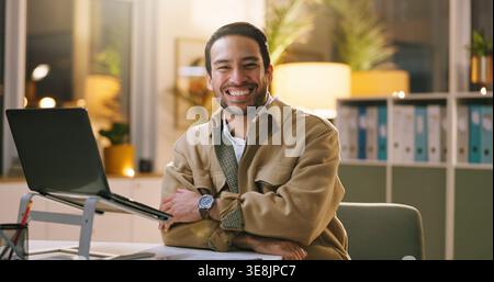 Creative, laptop and happy man with arms crossed in business, portrait or writer with pride at night. Newsroom, deadline and person with smile for Stock Photo