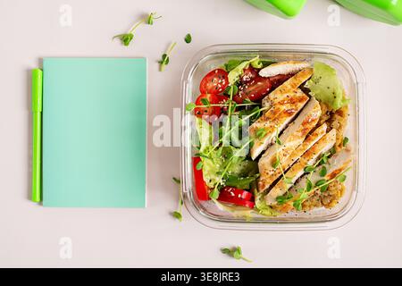Healthy lunch box with grilled chicken, lentils, and a fresh vegetable salad. Notebook and pen. Weight loss plan. Top view Stock Photo