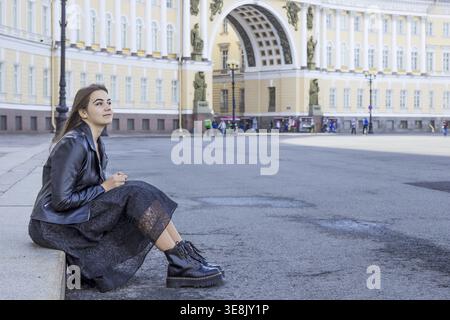 Portrait beautiful young woman in elegant black dress and boots on city street. Positive fashion lady in outdoor Stock Photo