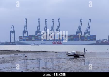 Boat stuck in silt, Harwich, container ship and container bridges in the background, Felixstowe Harbour, England, Great Britain Stock Photo