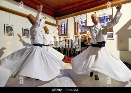 Whirling dervishes dance during a sufi performance in Istanbul. Musicians play traditional instruments in the background Stock Photo